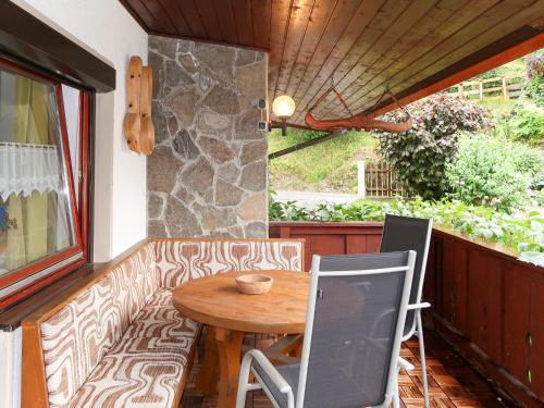 patio ze stołem i krzesłami oraz kamienną ścianą w obiekcie Apartment Zechner-3 by Interhome w mieście Tobadill