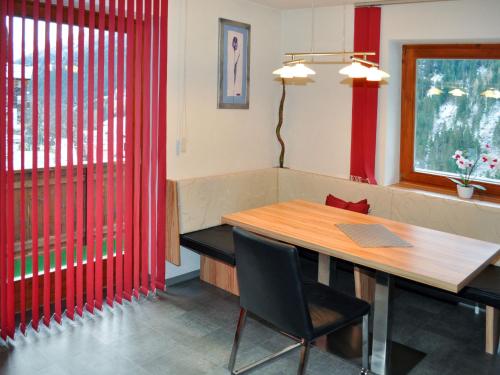 カップルにあるApartment Miramonte - KPL281 by Interhomeの赤いカーテンと木製テーブル付きのダイニングルーム