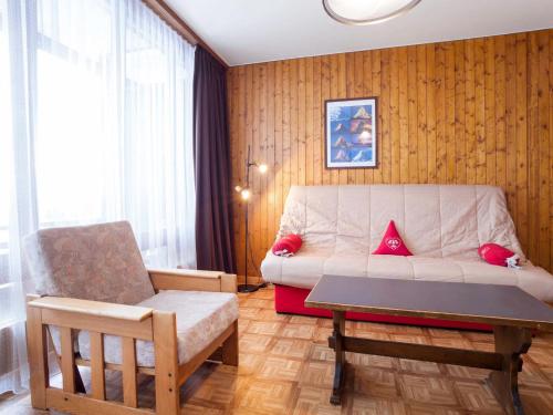 uma sala de estar com um sofá e uma cadeira em Studio Résidence Greppon by Interhome em Les Collons