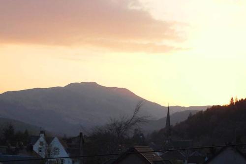 a sunset over a city with a mountain in the background at Andreu Cottage in Callander