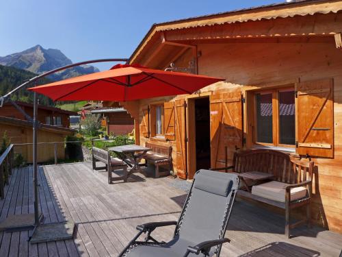 a deck with a table and chairs and an umbrella at Chalet Heiti N- 17 by Interhome in Gsteig