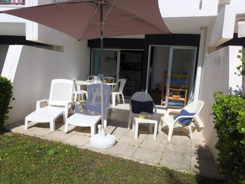 un groupe de chaises et un parasol sur une terrasse dans l'établissement Studio Ulysse Plage-4 by Interhome, à La Grande Motte