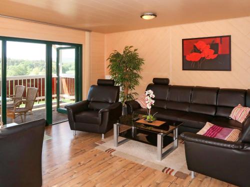 ein Wohnzimmer mit schwarzen Ledermöbeln und einem Balkon in der Unterkunft Holiday Home Erzeberg-3 by Interhome in Balhorn