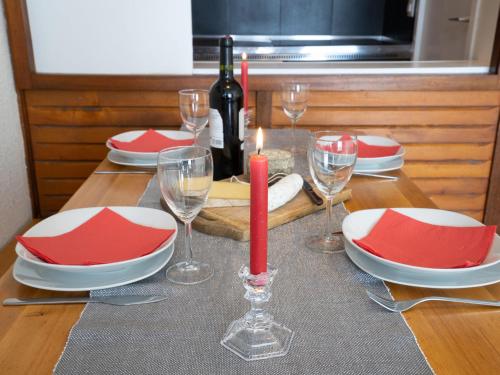 - une table avec une bougie rouge, des assiettes et des verres à vin dans l'établissement Apartment Le Borsat - Val Claret-4 by Interhome, à Tignes