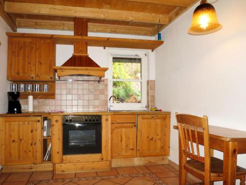 una cucina con armadi in legno, tavolo e finestra di Holiday Home Sonnenschein by Interhome a Hornberg