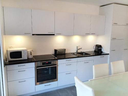 een keuken met witte kasten, een wastafel en een magnetron bij Apartment Bletilla by Interhome in Locarno