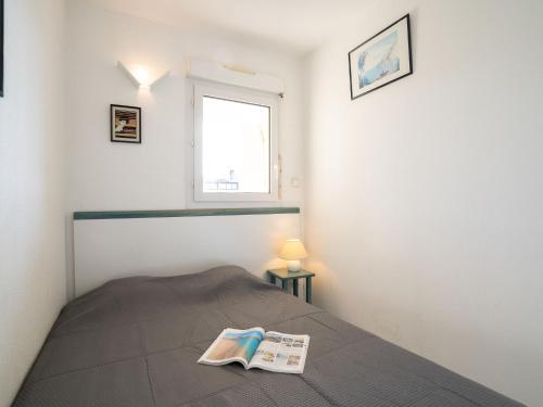 - une chambre avec un lit et un livre dans l'établissement Apartment La Palme d'Or-5 by Interhome, au Cap d'Agde