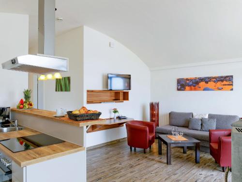 a kitchen and living room with red chairs and a couch at Holiday Home Dünenhaus Familia Comfort by Interhome in Großpösna