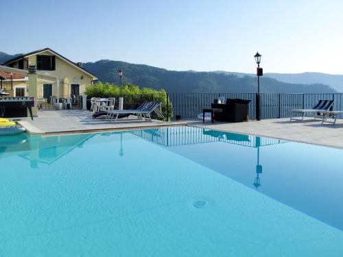 a large swimming pool with blue water in front of a house at Apartment Mimosa - VLO200 by Interhome in Lecchiore