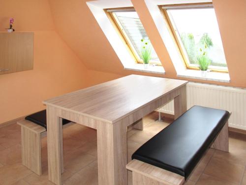 uma mesa de madeira e banco num quarto com duas janelas em Apartment Seeblick by Interhome em Verchen
