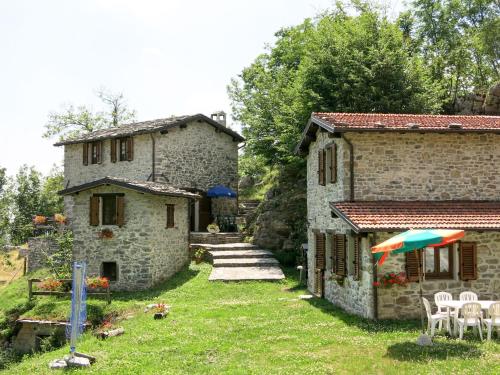 a stone house with a yard with chairs and an umbrella at Holiday Home Paradiso II by Interhome in Bolognana