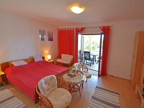 Schlafzimmer mit einem roten Bett, einem Tisch und Stühlen in der Unterkunft Apartment Matal by Interhome in Podorjak