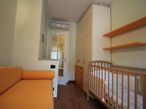 an orange couch in a room with a crib at Apartment Franco by Interhome in Porto Ceresio