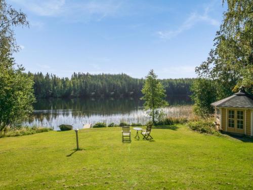 une cour avec deux chaises et une maison à côté d'un lac dans l'établissement Holiday Home Ahvenranta by Interhome, à Kosula