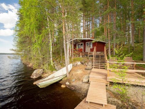 a cabin on the shore of a lake with a boat at Holiday Home Pohosniemi by Interhome in Huuhanaho