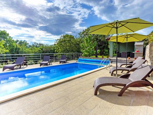 a swimming pool with chairs and an umbrella at Holiday Home Dante by Interhome in Marčelji
