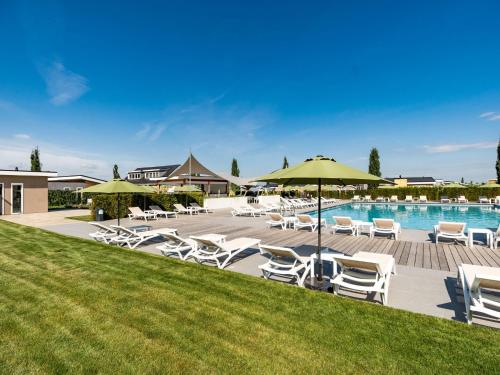 a pool with white lounge chairs and umbrellas at Holiday Home Green Resort Mooi Bemelen-1 by Interhome in Bemelen
