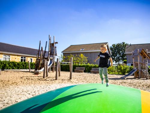 a young child jumping on top of a playground at Holiday Home Green Resort Mooi Bemelen-1 by Interhome in Bemelen