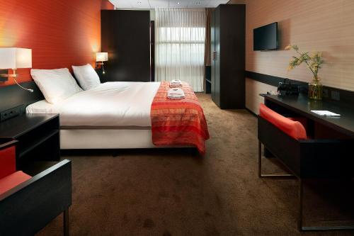 a hotel room with a bed and a desk at Hotel Babylon Heerhugowaard - Alkmaar in Heerhugowaard