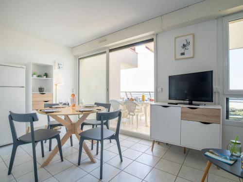 a living room with a table and chairs and a television at Apartment Le Sunset-Cap Sud-20 by Interhome in Cap d'Agde