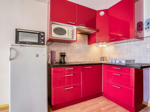 eine Küche mit roten Schränken und einem weißen Kühlschrank in der Unterkunft Studio Quai d'Honneur-2 by Interhome in Cap d'Agde