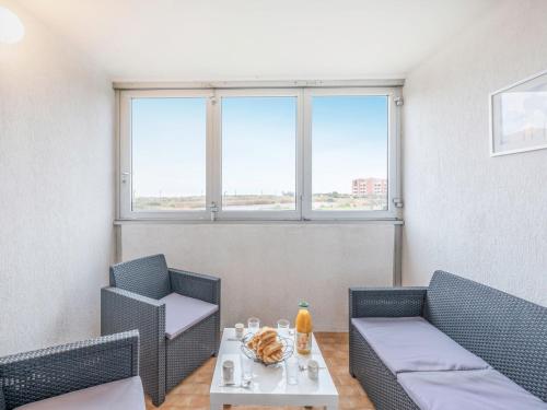 um quarto com duas cadeiras e uma mesa e duas janelas em Apartment Les terrasses de la Plage-4 by Interhome em Cap d'Agde