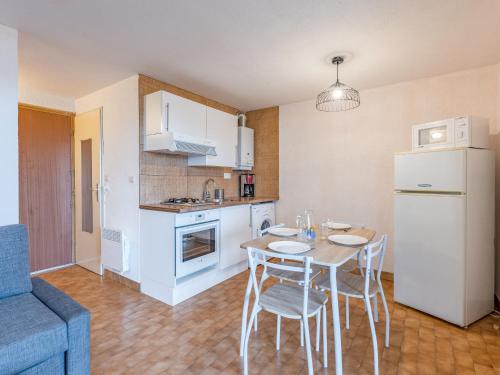 une cuisine avec une table, des chaises et un réfrigérateur dans l'établissement Apartment Les terrasses de la Plage-4 by Interhome, au Cap d'Agde