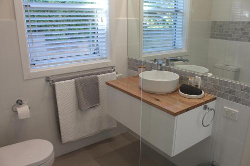 a bathroom with a sink and a toilet and two windows at Rosa's Apartment in Mount Gambier
