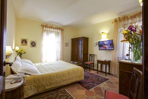 a bedroom with a bed and a desk and a window at Relais Castello di Razzano in Alfiano Natta
