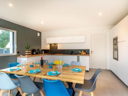 a kitchen and dining room with a wooden table and blue chairs at Holiday Home Villa Lanka by Interhome in Arzon