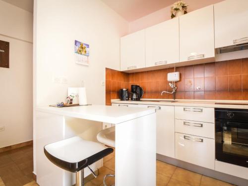 a kitchen with white cabinets and a stool at Holiday Home Marija by Interhome in Rovanjska