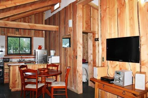 a kitchen with a table and a television in a cabin at Cabañas Peumayén Neltume in Neltume