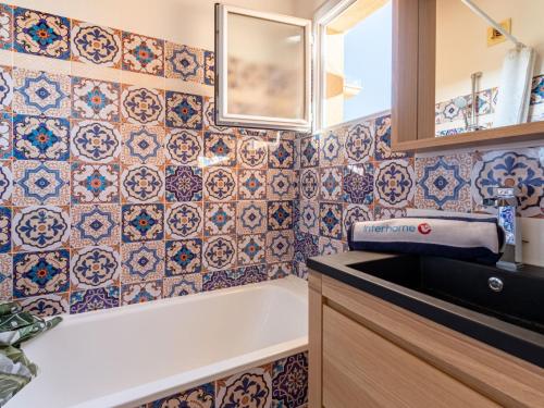 La salle de bains est pourvue d'une baignoire et de carrelage sur le mur. dans l'établissement Apartment Le Lagon Bleu-9 by Interhome, à Fréjus