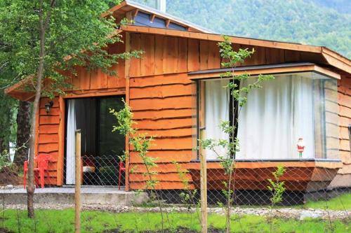 a wooden cabin with a fence in front of it at Cabañas Peumayén Neltume in Neltume