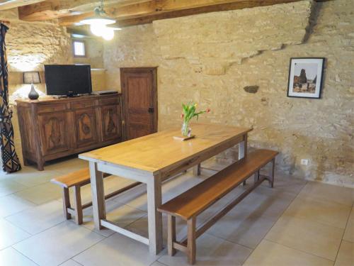 ein Esszimmer mit einem Holztisch und Bänken in der Unterkunft Holiday Home La Ferme by Interhome in Blanquefort-sur-Briolance