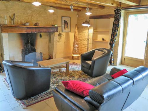 ein Wohnzimmer mit einem Ledersofa, Stühlen und einem Kamin in der Unterkunft Holiday Home La Ferme by Interhome in Blanquefort-sur-Briolance