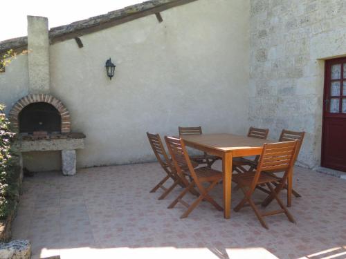 een patio met een tafel en stoelen en een open haard bij Holiday Home Le Pigeonnier Jacques by Interhome in Dondas