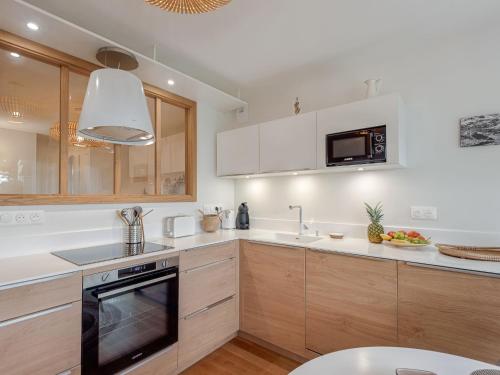 une cuisine avec des comptoirs blancs et des armoires en bois dans l'établissement Studio La Cormorane-6 by Interhome, à Carnac