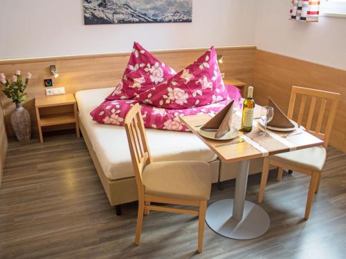 a room with a table and a couch with pink pillows at Apartment Bella Monte-4 by Interhome in Pettneu am Arlberg