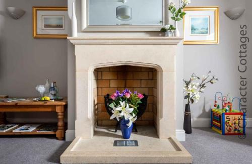 a fireplace with a vase with flowers in it at Birch House in Stow on the Wold