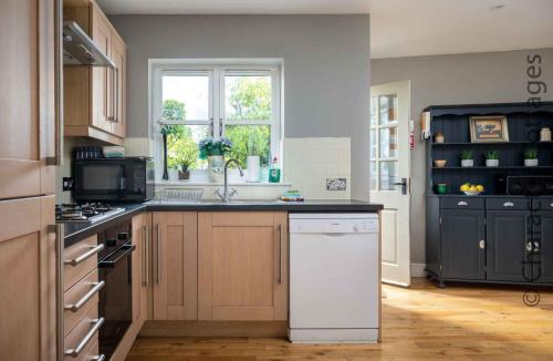 a kitchen with a white dishwasher and a window at Birch House in Stow on the Wold