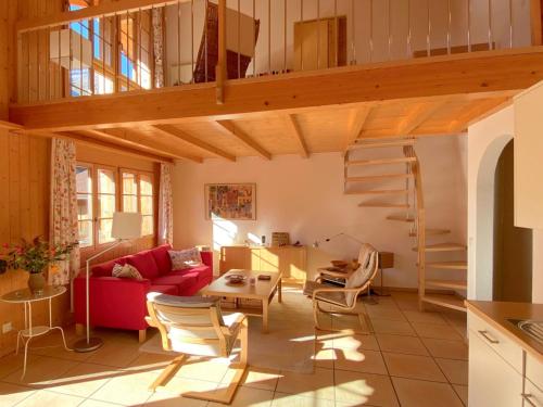 ein Wohnzimmer mit einem roten Sofa und einem Loft in der Unterkunft Apartment Haus Lohnerblick by Interhome in Kandersteg