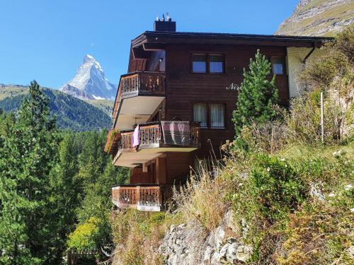ein Gebäude auf einem Hügel mit einem Berg im Hintergrund in der Unterkunft Apartment Nirwana by Interhome in Zermatt