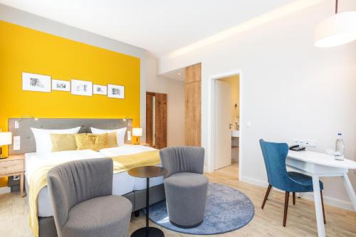 a bedroom with a bed and a desk and chairs at SEETELHOTEL Ostseehotel das Entdeckerhotel an der Ostsee und der perfekte Startpunkt für Ihre Inselabenteuer in Ahlbeck