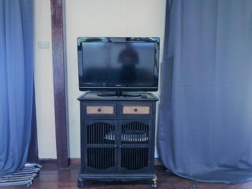 a tv sitting on a stand in a room with blue curtains at Lam Sai village hotel Koh Yao Noi in Ko Yao Noi