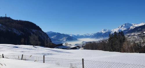 a snow covered mountain with a fence in the foreground at Appartement Lens in Lens