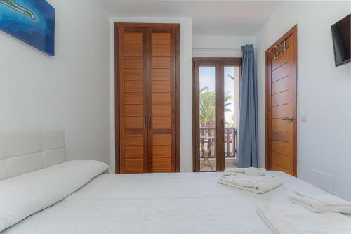 a white bedroom with a bed and a door at Casa Kaliste in Puerto Calero