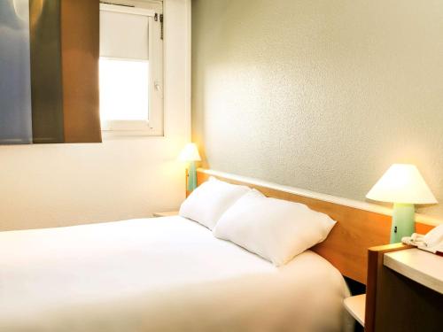 a bedroom with a bed with two pillows and a window at ibis Orange Centre in Orange