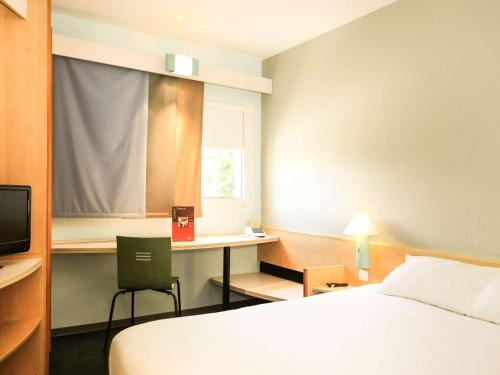 een hotelkamer met een bed en een bureau met een computer bij ibis Orange Centre in Orange