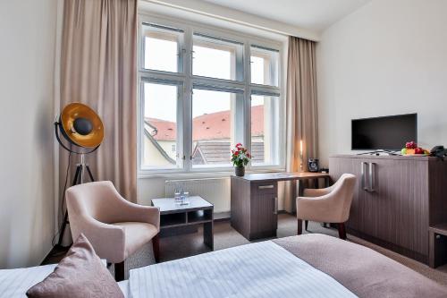 a hotel room with a bed and a desk and a window at Apartments Embassy by LH in Prague